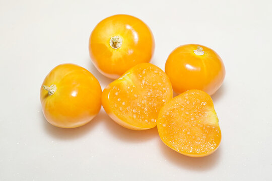 Close-up of yellow cape gooseberry fruits, with exposed and cut berries, set against white background
