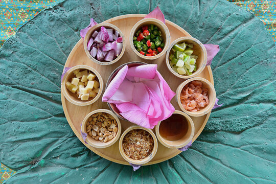 A Thai Miang kham bua lhuang platter with lotus flower petal wraps and a wide variety of ingredients, set on a decorative place mat