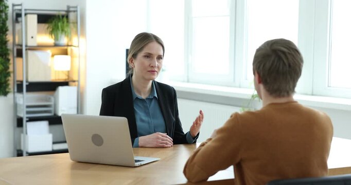 Recruiter with laptop and candidate having job interview at table in office