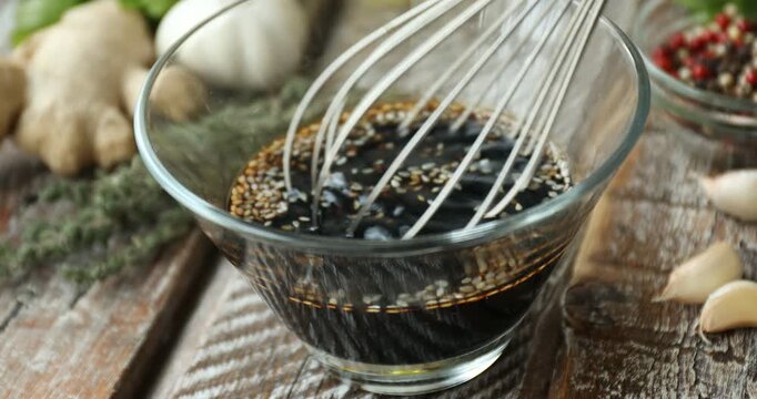 Making soy sauce marinade with whisk at wooden table, closeup