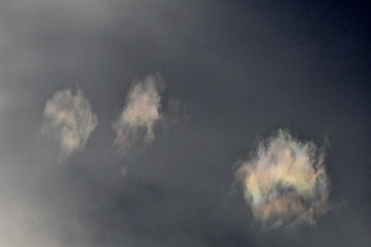 Three Clouds showing Iridescence, caused by diffraction of sunlight passing through thin clouds containing uniformly sized water droplets or ice crystals.