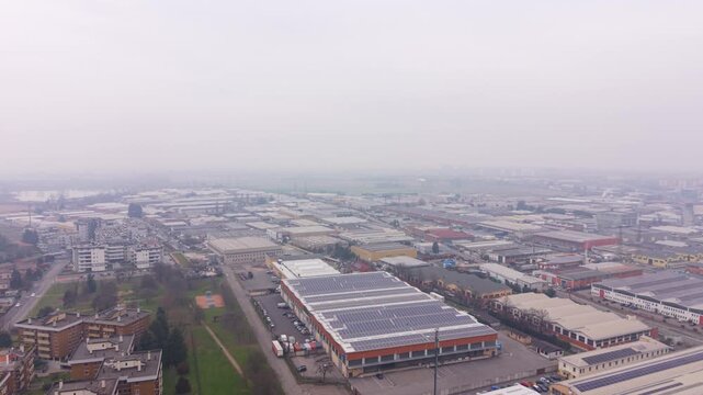 Aerial View of an Industrial Complex: A wide, high-angle view showcases a sprawling industrial complex, with its structured layout of buildings and logistical elements, enveloped under a diffused.