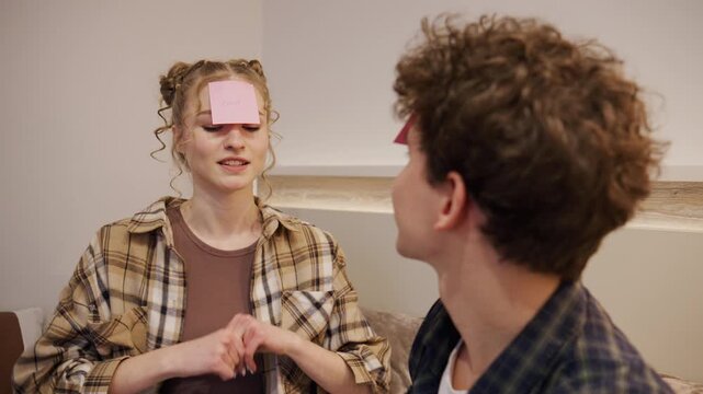 Group of friends play a guessing game in a living room during an evening gathering with sticky notes on their foreheads