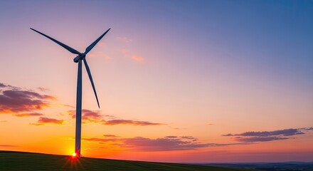 Obraz premium A wind turbine stands tall against a vibrant sunset sky, casting a silhouette against the horizon.