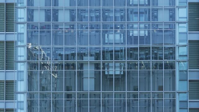 Moving elevators behind a blue glass curtain wall of a Tokyo office.