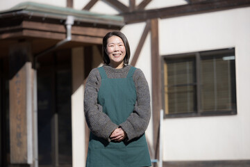 Obraz premium 地方移住で田舎で民宿やペンション、カフェを家族経営している女性のイメージ上半身 カメラ目線（多摩木材センター協同組合プロパティ許可ずみ）