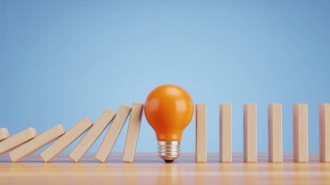 Orange lightbulb stopping domino effect on wooden table