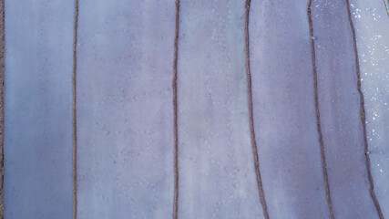 Top-down drone shot showing the unique mud textures and vertical lines of flooded paddy fields prepared for planting.