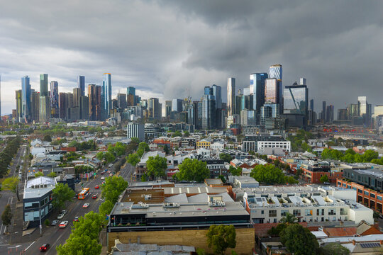Aerial view of dark storm clouds and rain moving over a distant city skyline