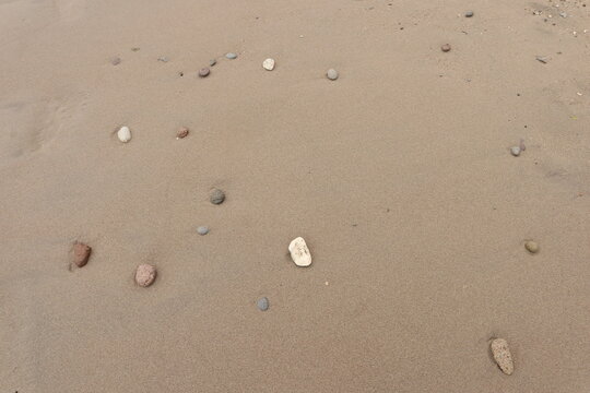 Small stones scattered on fine beach sand creating a natural minimalist texture background