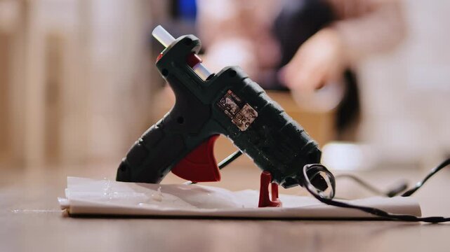 Hot glue gun warming up on table while person works on handmade project