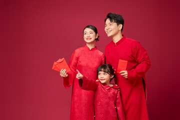Cheerful expressions, an Asian family holds red envelopes and looks in the same direction against...