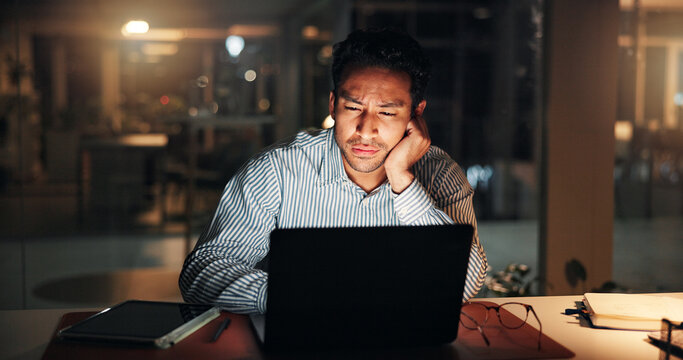 Man, tired and laptop at night in office with review, article or bored for deadline. Creative person, overtime and computer for research, feedback and exhausted for draft task in publishing company