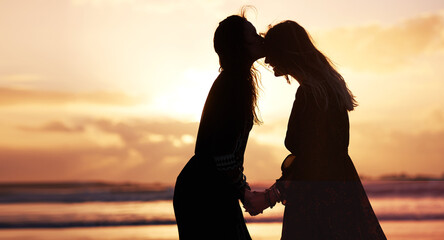 Women, kiss and sunset on beach for holiday, adventure and happiness at sea. Friends, travel and...