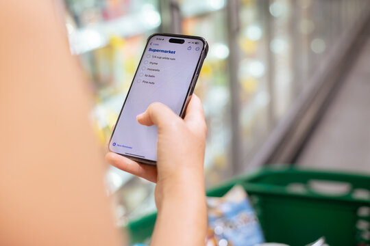 woman at the supermarket using phone shopping list