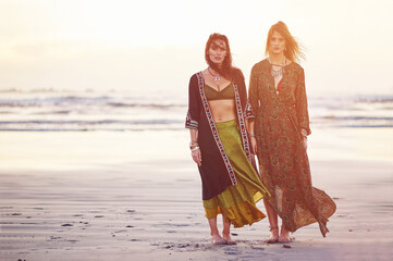 Fashion, portrait and space with women on beach together for holiday or vacation in boho clothing. Sky, sunset and travel with hippie friends outdoor on sand at coast for bonding or retro style