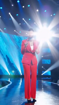 Performer in red suit on stage with vibrant lighting effects