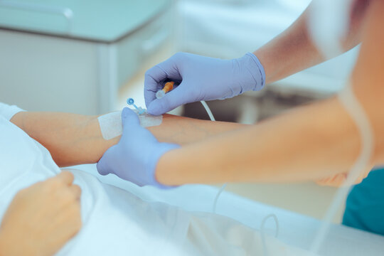 Medical Assistant inserting IV Cannula to a Patient for Treatment. Woman getting intravenous therapy for dehydration 