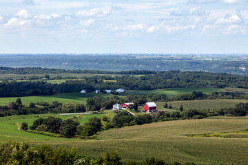 Obraz premium Rural Farmstead Valley with Red Barn Accent and Summer Fields