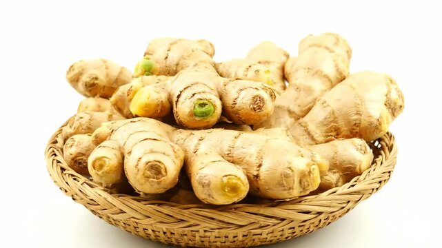 Fresh Ginger Root in Wicker Basket - A close-up shot of a basket overflowing with fresh ginger roots on a white background.