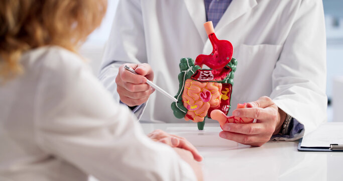 Female Doctor Explaining Colon Polyps To Upset Patient On Model