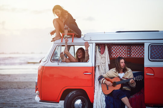 Happy, beach and friends in van for road trip, adventure and vacation together in summer outdoor. Guitar, hipster and men and women in vehicle for bonding on holiday, journey and travel destination