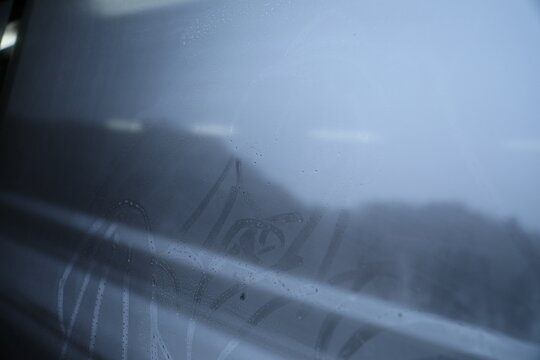 Finger drawing of Hello Kitty on a foggy window with condensation during winter travel.