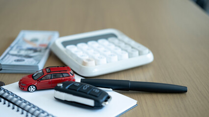 Minimal workspace with red car model, calculator and money on desk, symbolizing car loan calculation, auto insurance planning and financial management.