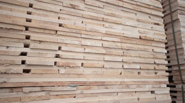 Close up of many stacked wooden planks in a warehouse or construction site. Natural timber boards prepared for building and carpentry industry. Industrial woodwork and lumber material.