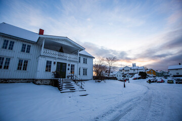 Svolvear, Lofoten Island, Norway House with a porch and steps is covered in snow. The sky is cloudy and the sun is setting