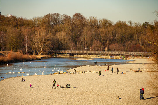 Scene at the Flaucher in Munich, known for its extensive gravel banks. In the background, the Flauchersteg, a striking wooden bridge for pedestrians that crosses the Isar River.