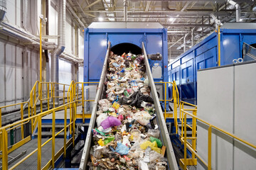A conveyor belt filled with household waste for recycling is lifted up for sorting.