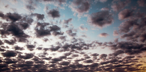 the evening sky is a beautiful blend. of blue sunlight and an orange horizon, with soft, fluffy clouds.