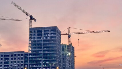 Construction site with towering cranes and multi-story residential buildings under development...