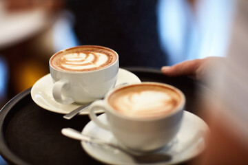Fototapeta premium Hands, person and server with coffee in cafe for client order, customer service and hospitality. Closeup, employee and serving beverage for catering, espresso drinks and delivery in restaurant