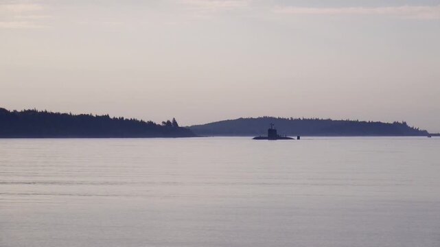 Wide shot of a submarine entering Halifax Harbour with city and harbor surroundings