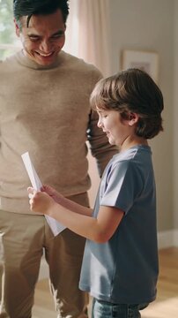 Boy showing his report card to his smiling father at home, vertical shot