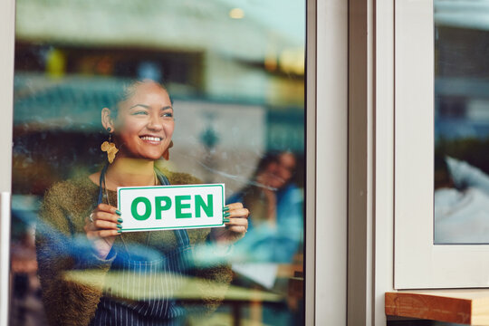 Open sign, glass door and smile with woman in cafe for hospitality, small business and storefront. Restaurant notice, entrepreneur signage and manager with person in coffee shop for retail startup
