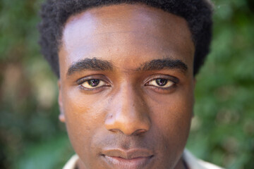 Obraz premium African american man posing for portrait shoot in park in collared shirt with foliage backdrop