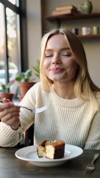 Young woman enjoying a slice of cake in a cozy caf&eacute; setting, vertical shot
