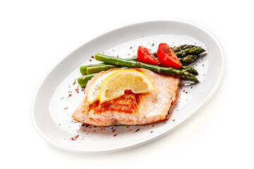 Garnished fried salmon steak with boiled green asparagus on white background