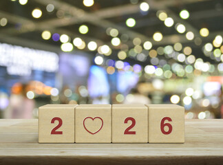 Love flat icon with 2026 letter on wood block cubes on wooden table over blur light and shadow of shopping mall, Happy new year 2026 and Valentines day concept