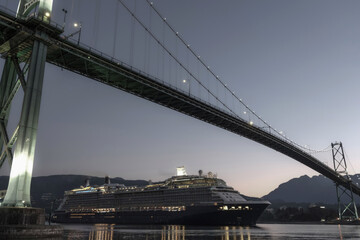 Fototapeta premium Modern luxury cruiseship cruise ship liner Solstice returning to Vancouver, BC Canada from Alaska cruise during sunrise early morning blue hour harbor landscape marine traffic city skyline silhouette