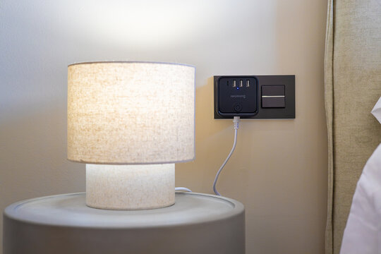 Modern bedroom corner with fabric table lamp and wall-mounted USB charging station