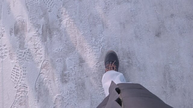 A person walks along a snowy path leaving footprints in the fresh snow.