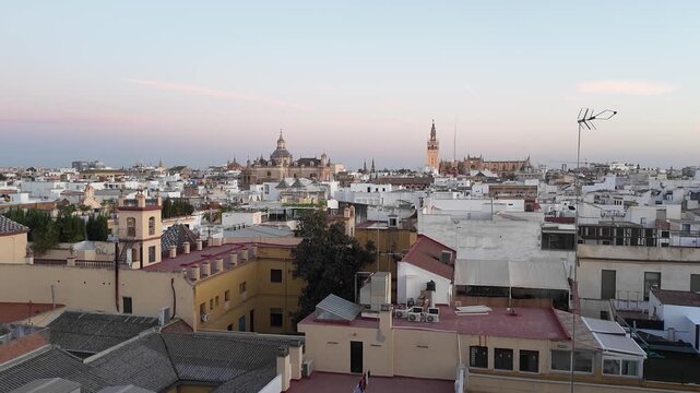 NEED YOUR ATENTION -A captivating sunset Timelapse captures the changing light over the rooftops of a historic Spanish city, utilizing a Zoom In to highlight the iconic cathedral tower on the horizon.