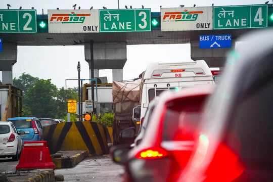 Vehicles passing through an Indian highway toll plaza with FASTag lanes, showing modern road infrastructure, traffic flow, and digital toll collection.