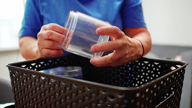 Hands placing a glass container into a basket in a home setting with natural light