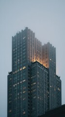 Towering building shrouded in fog at dusk