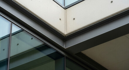 Fototapeta premium Corner detail of modern concrete building with glass windows and black metal frames